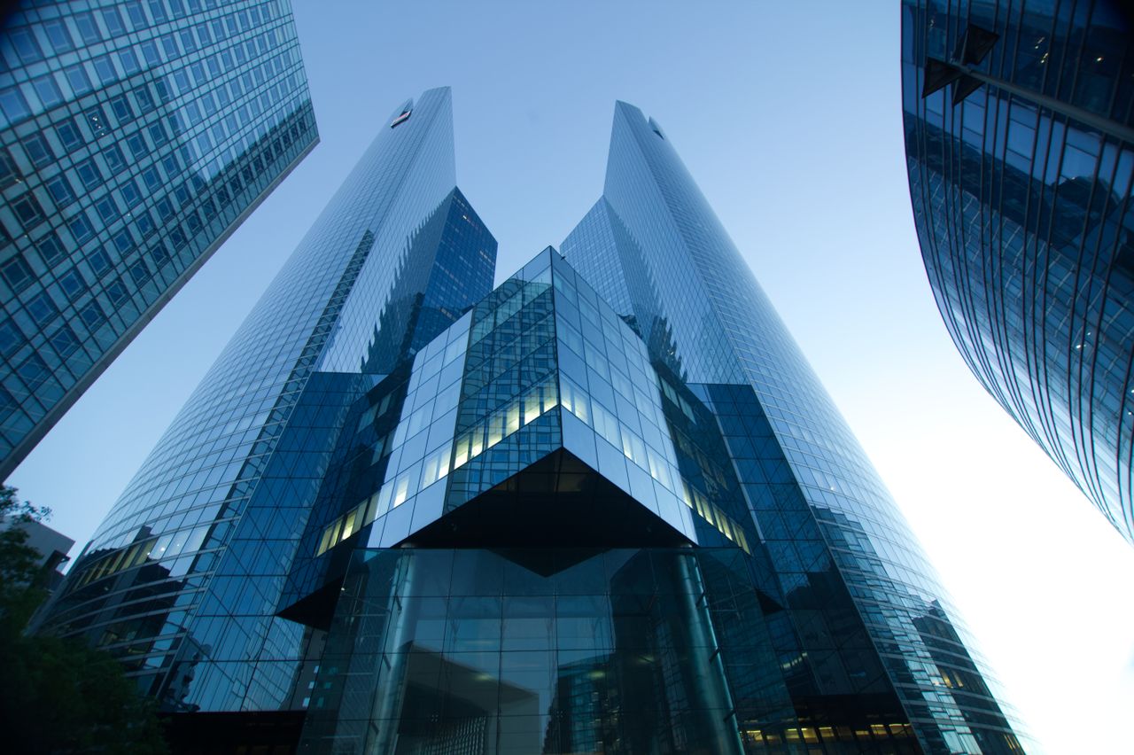 Low-angle view of modern glass skyscrapers reflecting a clear blue sky. Perfect for urban and architectural themes.