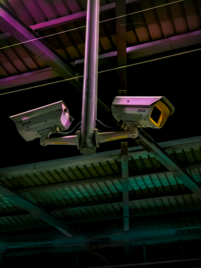 About Pair of security cameras installed in an industrial setting with vibrant lighting.
